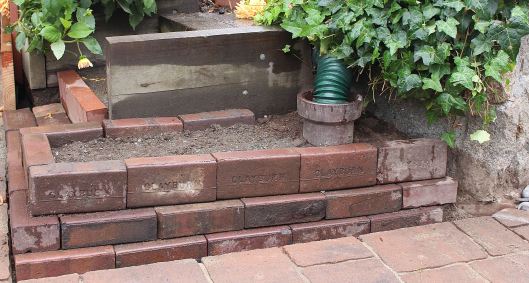 We also rebuilt this brick wall surrounding a drainage pipe. For Leslie, it's a new planting area.